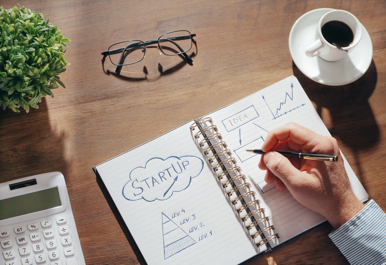 services-01 A creative workspace featuring startup planning on a notepad, eyeglasses, and a cup of coffee.