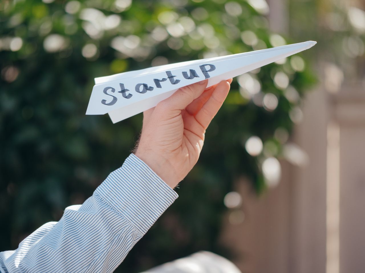 services-03 Close-up of a hand holding a paper plane with 'Startup' written, symbolizing a business launch.