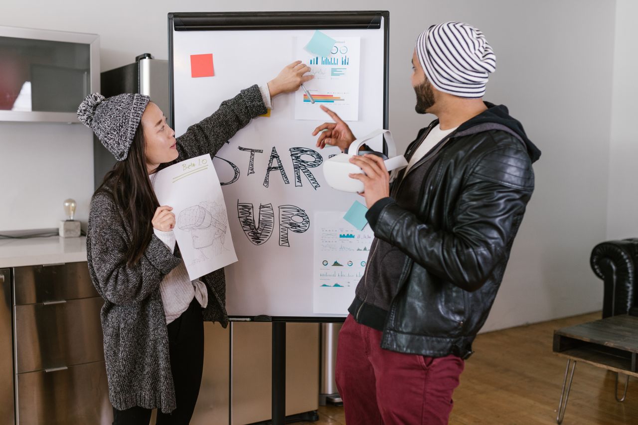 about-02 Two young adults presenting startup business ideas on a flipchart indoors.